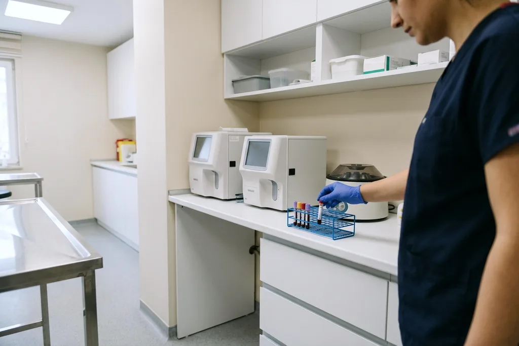 Klinik laboratuvarında kan analiz cihazına numune yerleştiren el
